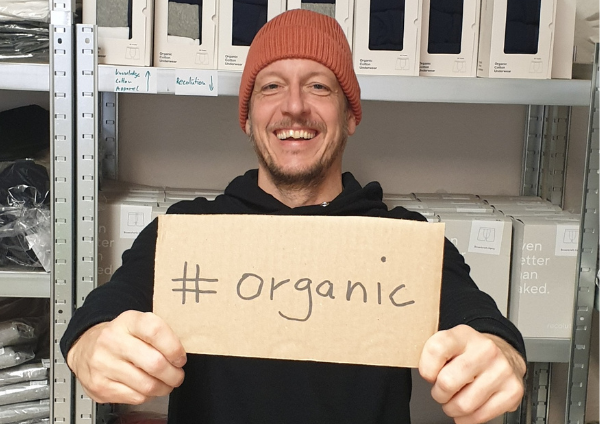 Der green.in.pieces Gründer Daniel hält ein Schild mit der Aufschrift organic in die Kamera